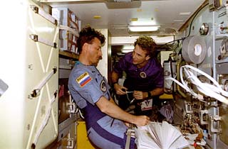 STS-84 Mission Specialist Jerry Linenger and Mir-23 crewmember Michael Foale conduct transfer ops in the Mir Space Station Priroda module. 